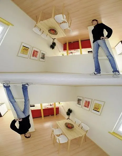 man standing in an upside down house 